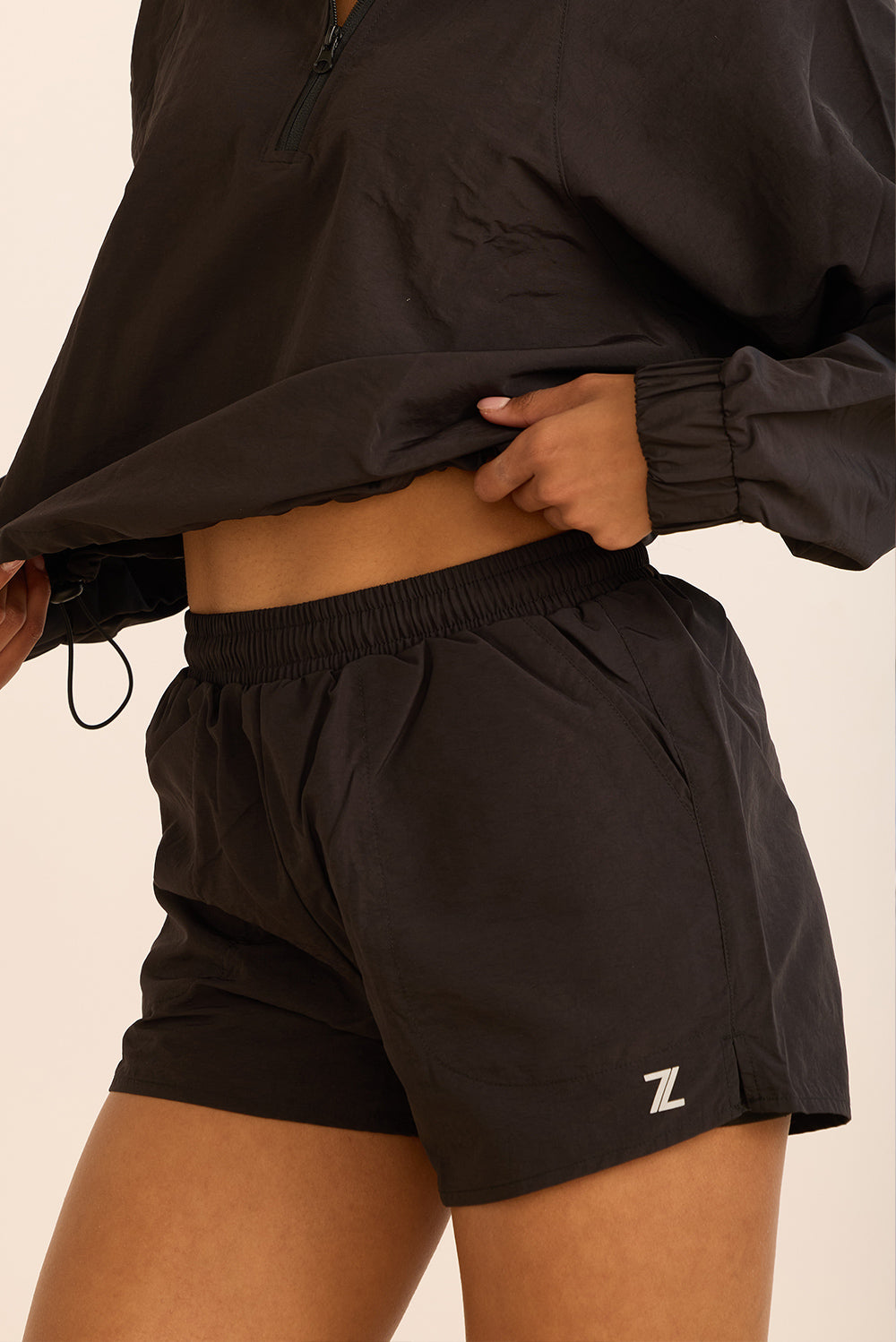 שורט מבד ניילון בשילוב טייץ פנימי קצר, שרוכי קשירה וכיסים צדדים בגוון שחור