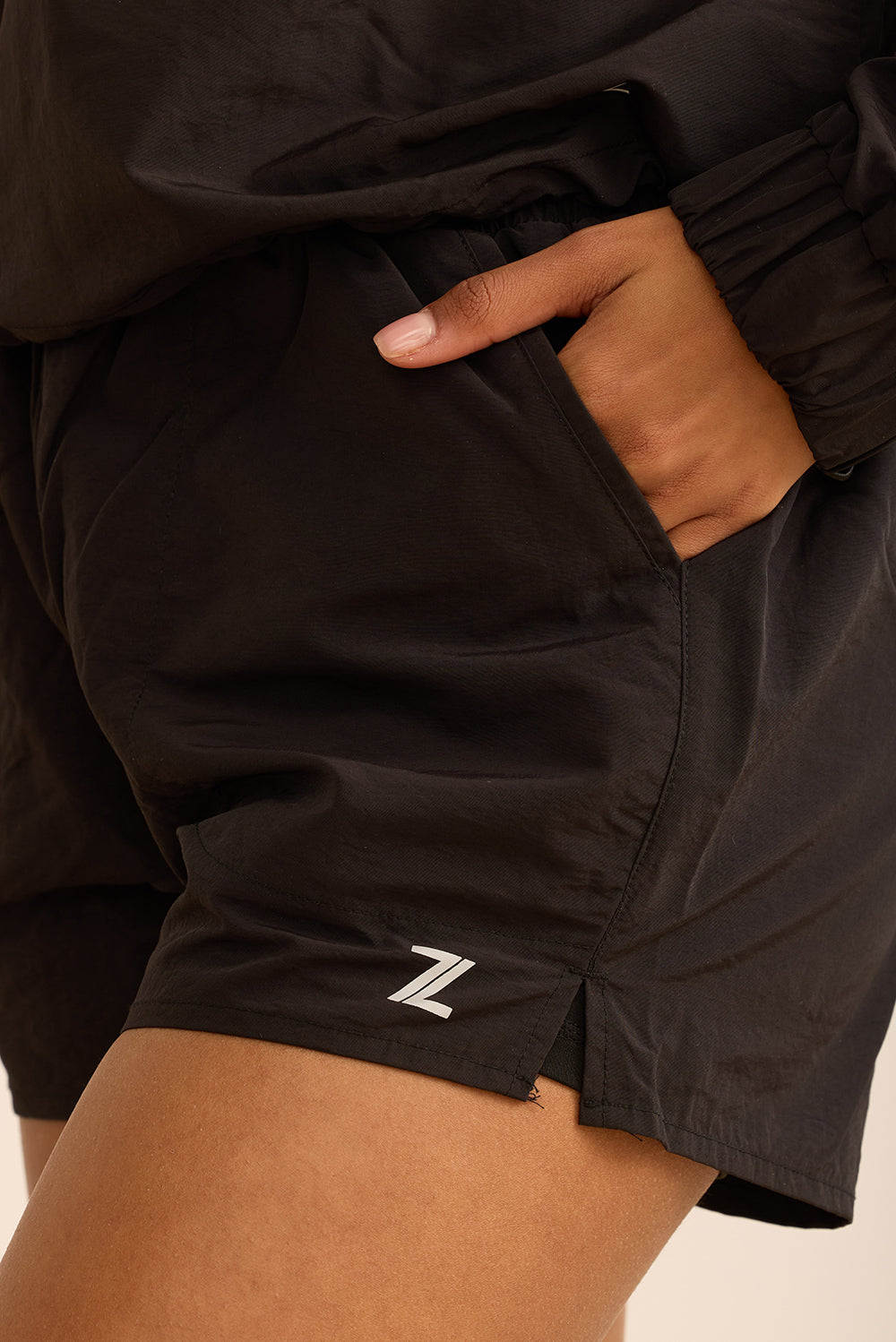 שורט מבד ניילון בשילוב טייץ פנימי קצר, שרוכי קשירה וכיסים צדדים בגוון שחור