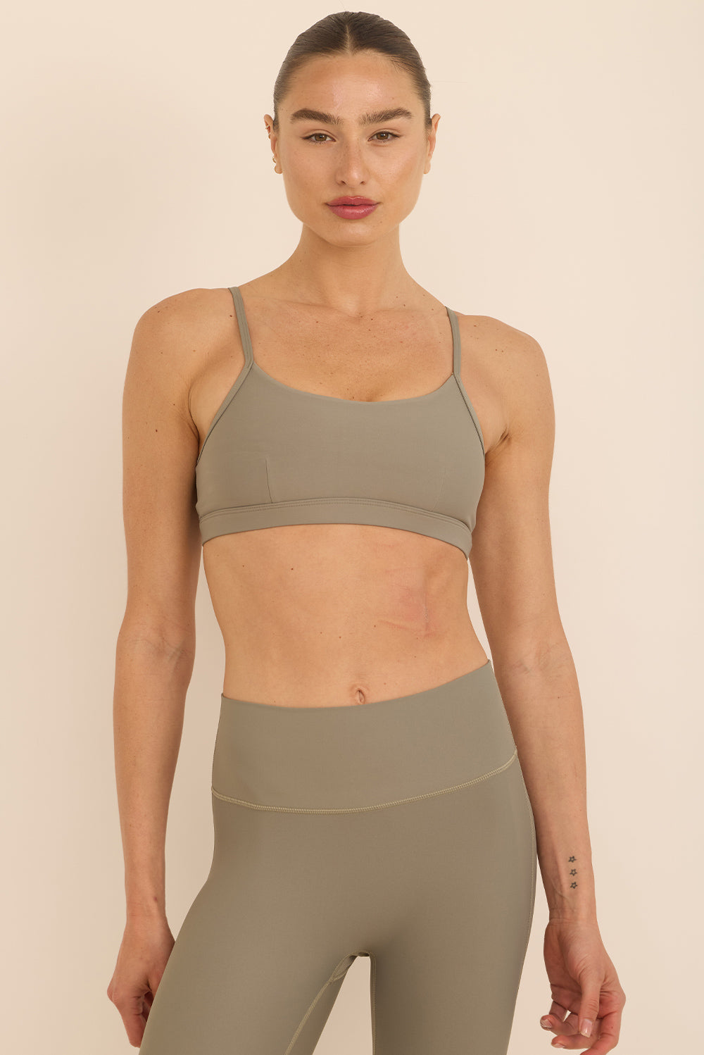 טופ מבד 4 כיוונים בשילוב רצועות מתכוונות, וריפוד נשלף בגוון ירקרק, מהסדרה בעיצובה של עינב כהן