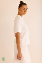 חולצה  מבד סקובה בגוון לבן,  צווארון עגול וסגור, אורך השרוול עד לתחילת המרפק- תמונה לצד