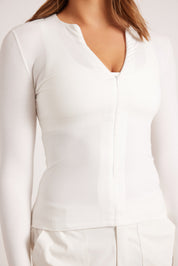 חולצת שרוול ארוך בגוון לבן, פתיחת רוכסן מקדימה (לא עד הסיומת).
