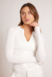 חולצת שרוול ארוך בגוון לבן, פתיחת רוכסן מקדימה (לא עד הסיומת).