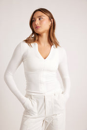 חולצת שרוול ארוך בגוון לבן, פתיחת רוכסן מקדימה (לא עד הסיומת).