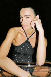 בגד גוף מבד 4 כיוונים.התחתון למטה הוא בגזרה חוטיני.הבגד גוף ללא שכבה פנימית באזור החזה.הבגד גוף ללא ריפוד נשלף וגם ללא תיקתקים.בגב הבגד גוף בהיעדר מתיחה הפתח בגב יכול להיות רופף.גוון שחור עם נקודות בגוון קרם.