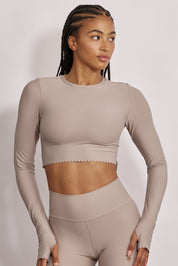 חולצת קרופ שרוול ארוך מהקולקציה בעיצובה של אדל בספלוב, בשילוב של חיתוכי לייזר, חיתוך לב בפריט ללא שכבה פנימית, מקום לאגודל, גוון שחור.