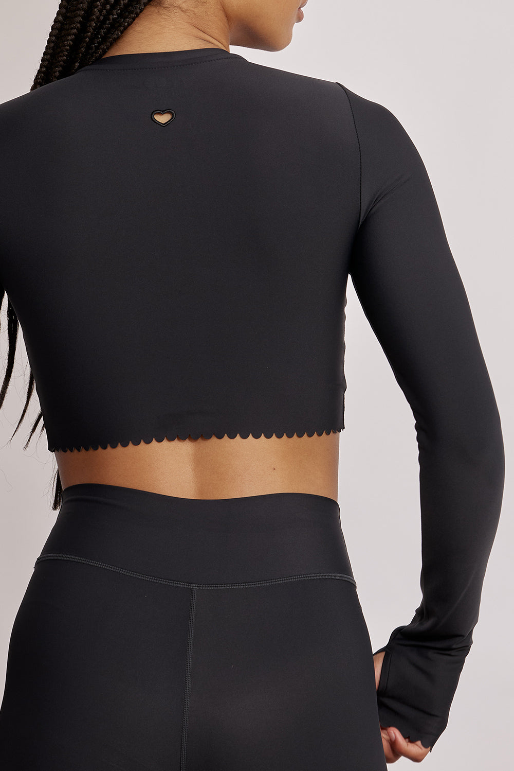 חולצת קרופ שרוול ארוך מהקולקציה בעיצובה של אדל בספלוב, בשילוב של חיתוכי לייזר, חיתוך לב בפריט ללא שכבה פנימית, מקום לאגודל, גוון שחור.