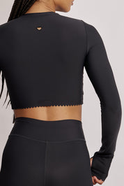 חולצת קרופ שרוול ארוך מהקולקציה בעיצובה של אדל בספלוב, בשילוב של חיתוכי לייזר, חיתוך לב בפריט ללא שכבה פנימית, מקום לאגודל, גוון שחור.