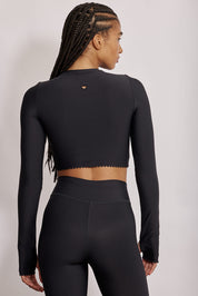 חולצת קרופ שרוול ארוך מהקולקציה בעיצובה של אדל בספלוב, בשילוב של חיתוכי לייזר, חיתוך לב בפריט ללא שכבה פנימית, מקום לאגודל, גוון שחור.