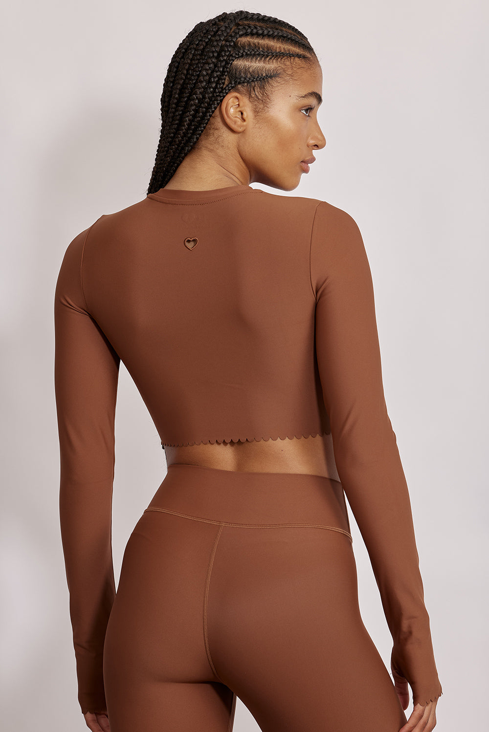 חולצת קרופ שרוול ארוך מהקולקציה בעיצובה של אדל בספלוב, בשילוב של חיתוכי לייזר, חיתוך לב בפריט ללא שכבה פנימית, מקום לאגודל, גוון חום.