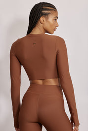 חולצת קרופ שרוול ארוך מהקולקציה בעיצובה של אדל בספלוב, בשילוב של חיתוכי לייזר, חיתוך לב בפריט ללא שכבה פנימית, מקום לאגודל, גוון חום.