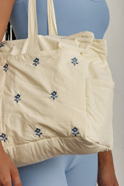 EINAV'S DREAM BAGתיק גדול ומרווח בגוון שמנת.עיצוב עם רקמת דפוס פרחוני בגוון כחול.עשוי מבד קליל רך ונעים מגע.מתאים לשימוש יומיומי.ידיות נשיאה.כולל רצועה ייעודיות פנימית לתלייה על התיק על עגלת תינוק.כיסים חיצוניים: אחד קדמי, אחד אחורי.כיסים צדדים: אחד בכל צד.הכיסים החיצוניים לא נסגרים עם כפתור או רוכסן.התיק נפתח עם רוכסן, ויש גם תיק תק בכל צד להרחבת התיק.בתוך התיק ישנו 3 כיסים בכל צד (סה״כ 6) ללא כפתור או סגירה.גודל: כ- 50 רוחב, כ- 40 אורך.