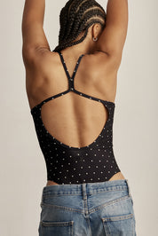 בגד גוף מבד 4 כיוונים.התחתון למטה הוא בגזרה חוטיני.הבגד גוף ללא שכבה פנימית באזור החזה.הבגד גוף ללא ריפוד נשלף וגם ללא תיקתקים.בגב הבגד גוף בהיעדר מתיחה הפתח בגב יכול להיות רופף.גוון שחור עם נקודות בגוון קרם.